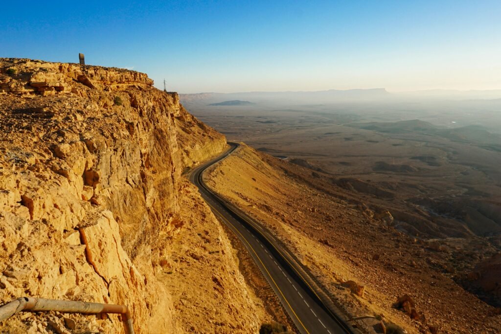 Explore the breathtaking arid landscape of the Mitzpe Ramon Crater with a winding road and expansive desert views.