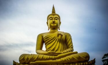 A majestic golden Buddha statue against a serene blue sky, symbolizing peace and spirituality.