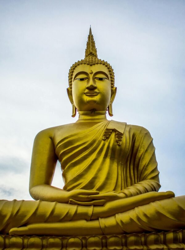 A majestic golden Buddha statue against a serene blue sky, symbolizing peace and spirituality.