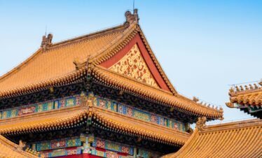 Close-up of the ornate roof architecture of Beijing's Forbidden City, showcasing detailed carvings and vibrant colors.