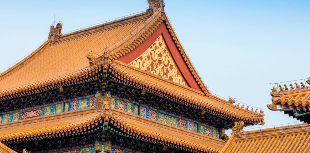 Close-up of the ornate roof architecture of Beijing's Forbidden City, showcasing detailed carvings and vibrant colors.