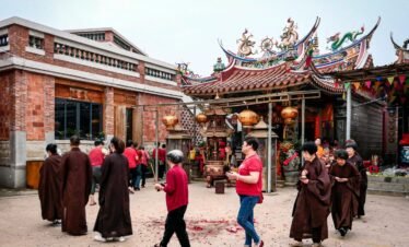 People participating in a spiritual ritual outside a traditional Asian temple.