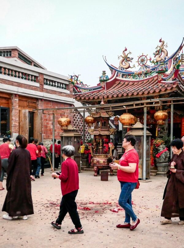 People participating in a spiritual ritual outside a traditional Asian temple.