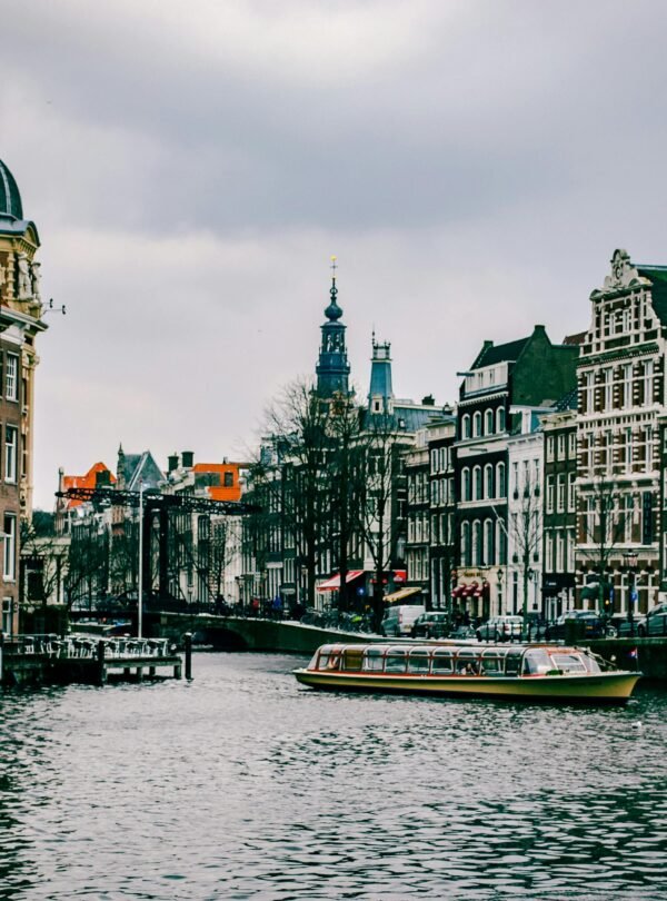 Charming canal scene in Amsterdam with historic architecture and a passing boat.