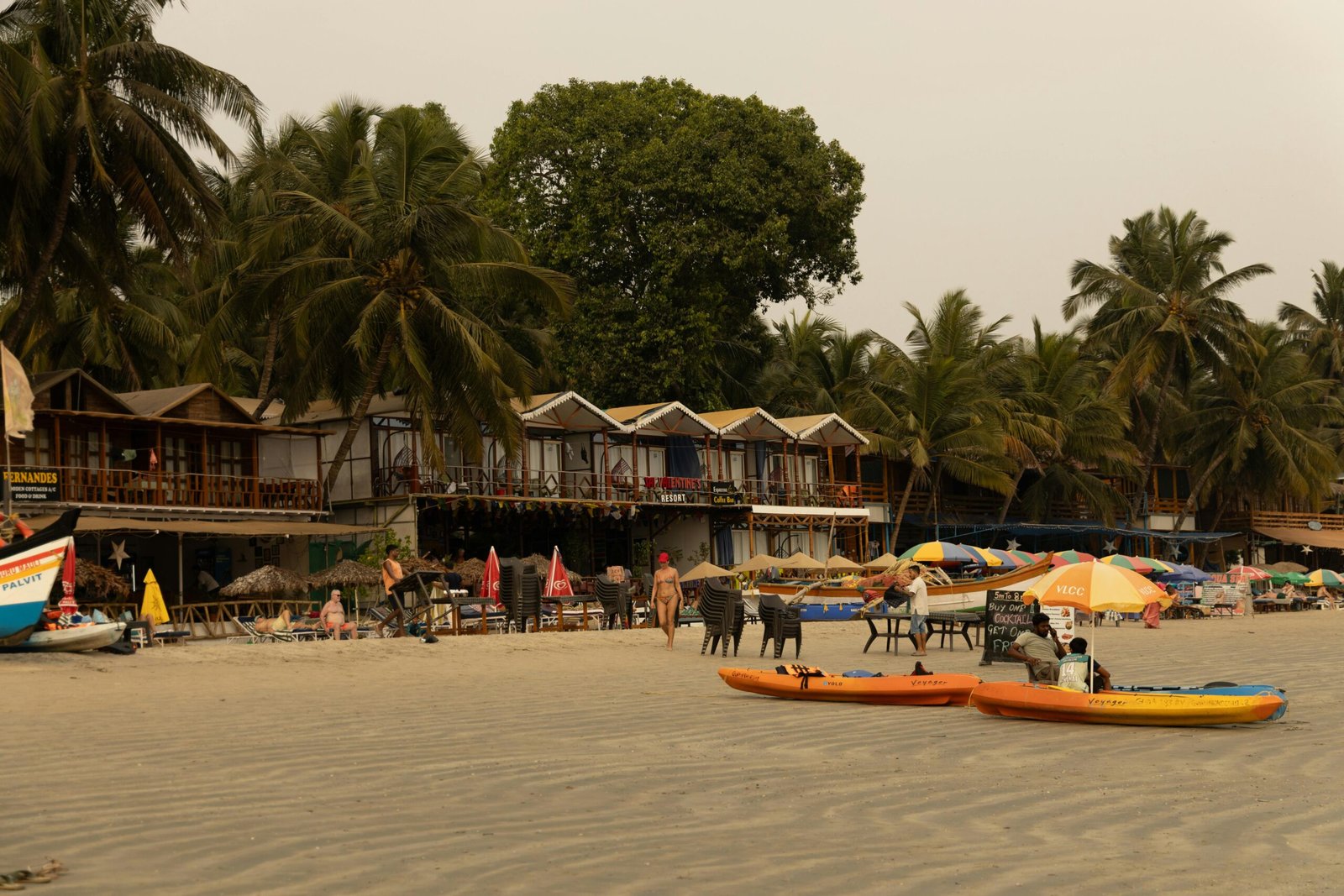 Relaxing beachfront with colorful kayaks, palm trees, and vibrant outdoor seating in tropical setting.