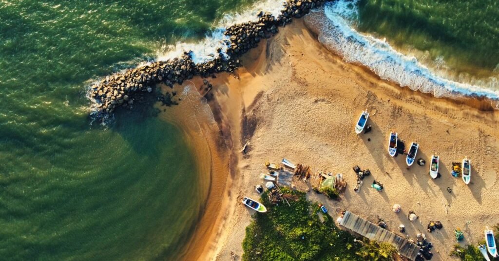 Stunning drone shot of Katuneriya Beach featuring boats, crashing waves, and tetrapods.