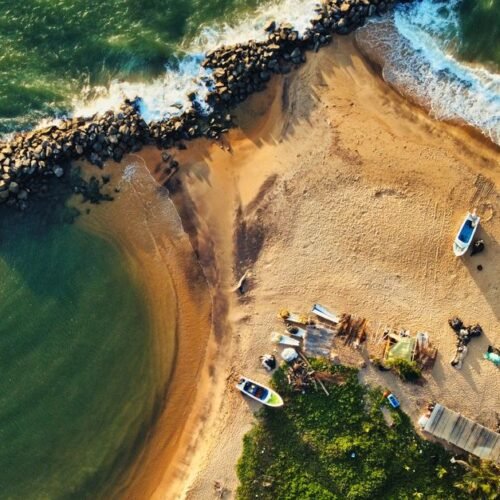 Stunning drone shot of Katuneriya Beach featuring boats, crashing waves, and tetrapods.
