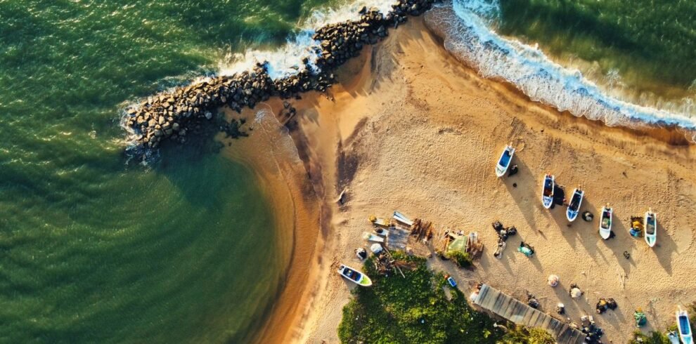 Stunning drone shot of Katuneriya Beach featuring boats, crashing waves, and tetrapods.