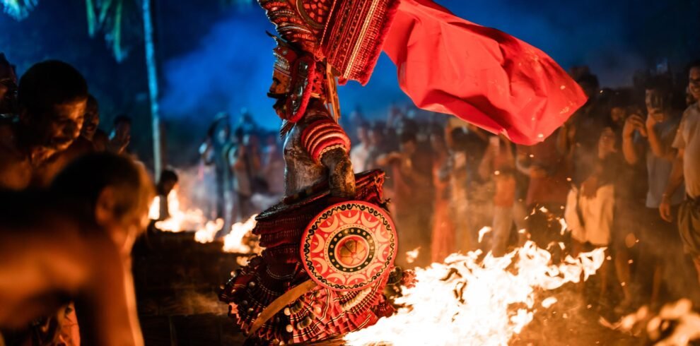 A vivid portrayal of Theyyam ceremony in Udinur, India, amidst fire and vibrant costumes at night.
