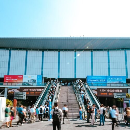 People entering Shanghai exhibition center via outdoor escalator during daytime.