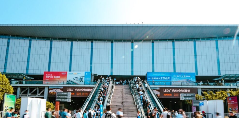 People entering Shanghai exhibition center via outdoor escalator during daytime.