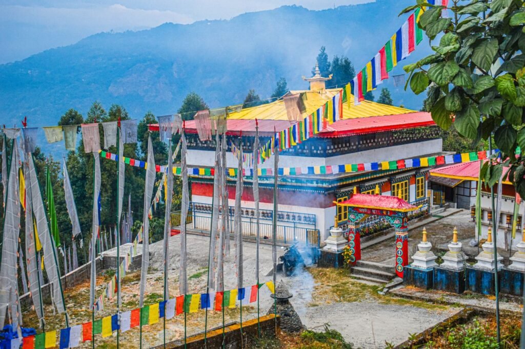 Colorful Buddhist temple surrounded by prayer flags in the misty Himalayan mountains.