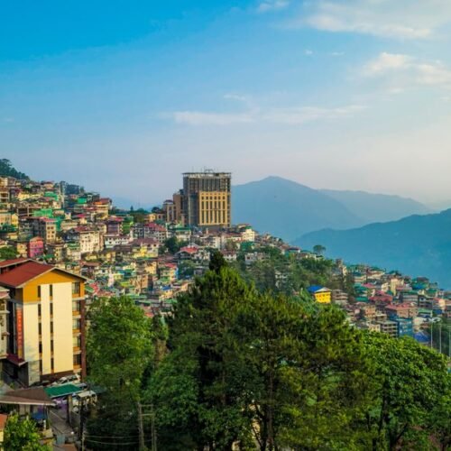 Vibrant view of Gangtok's hillside architecture with lush green surroundings under a clear sky.