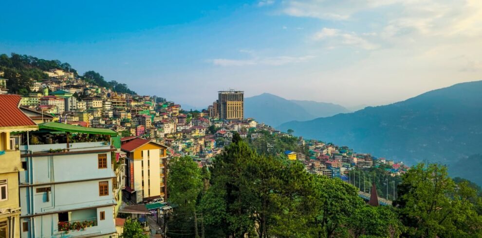 Vibrant view of Gangtok's hillside architecture with lush green surroundings under a clear sky.