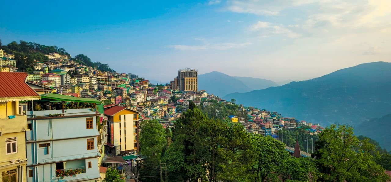 Vibrant view of Gangtok's hillside architecture with lush green surroundings under a clear sky.