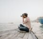 A man taking photos while seated on a boat by the water, capturing scenic views and enjoying leisurely travel.