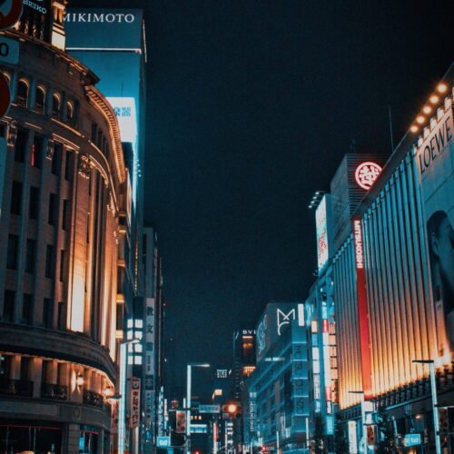 Experience the vibrant nightlife of Ginza, Tokyo, in this stunning street view illuminated by towering neon lights.