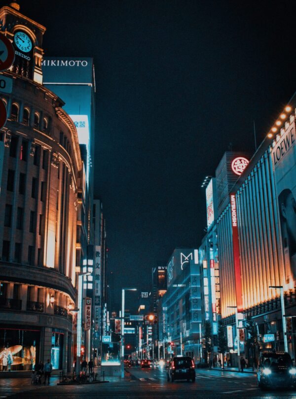 Experience the vibrant nightlife of Ginza, Tokyo, in this stunning street view illuminated by towering neon lights.