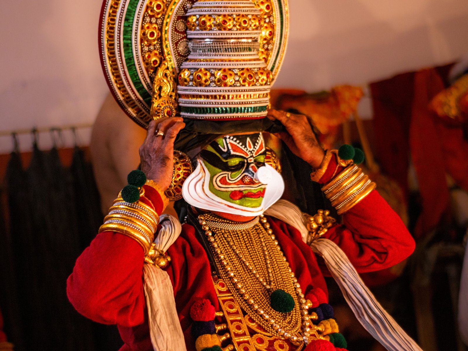 A Kathakali performer donning traditional attire and face makeup backstage, capturing the essence of Indian classical dance.