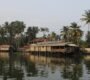 Tranquil Kerala backwaters with houseboats and palm trees at sunrise.