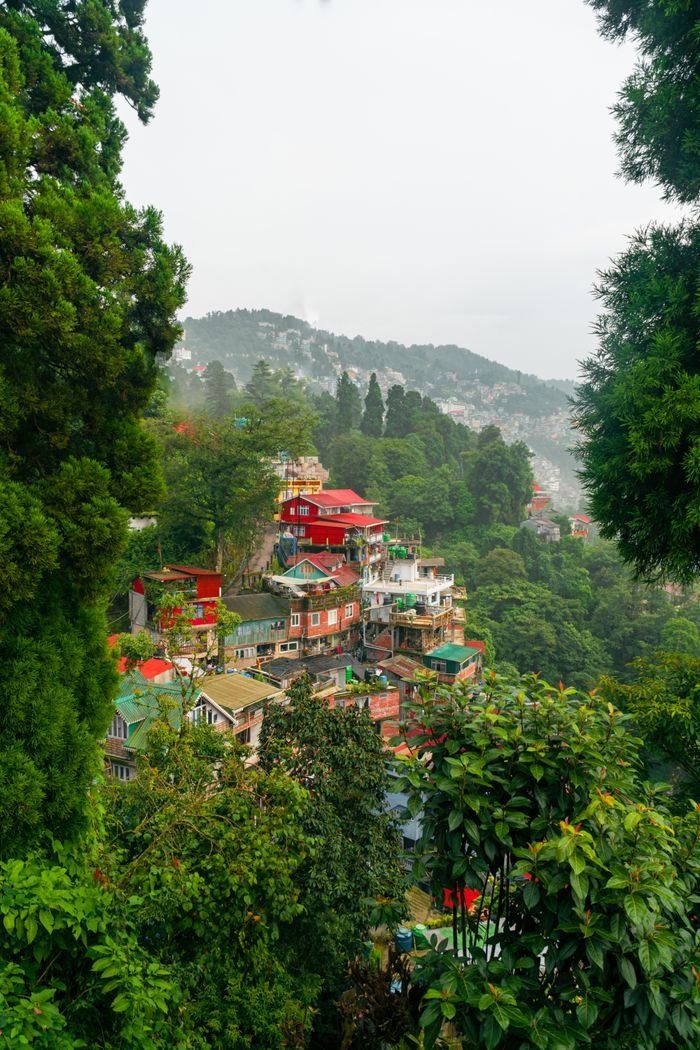 Charming hill houses nestled in lush greenery in Darjeeling, West Bengal during monsoon.