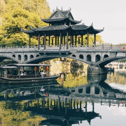 Beautiful traditional Chinese bridge over a reflective lake with lush surroundings.