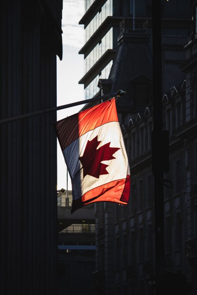 A Canadian flag waving prominently in a sunlit street in London, showcasing cultural diversity.