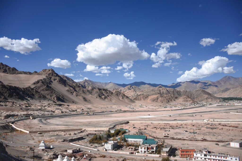 Explore the breathtaking landscape of Leh Ladakh, capturing the rugged mountains and vast desert terrain under a clear blue sky.