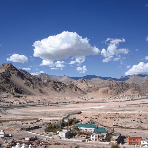 Explore the breathtaking landscape of Leh Ladakh, capturing the rugged mountains and vast desert terrain under a clear blue sky.