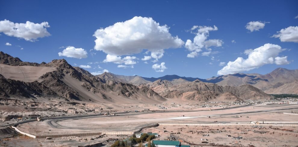 Explore the breathtaking landscape of Leh Ladakh, capturing the rugged mountains and vast desert terrain under a clear blue sky.