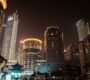 Vibrant city skyline at night with illuminated skyscrapers and modern architecture.