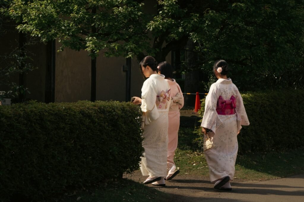 Three women in traditional kimonos strolling in a serene Tokyo garden, capturing cultural elegance.