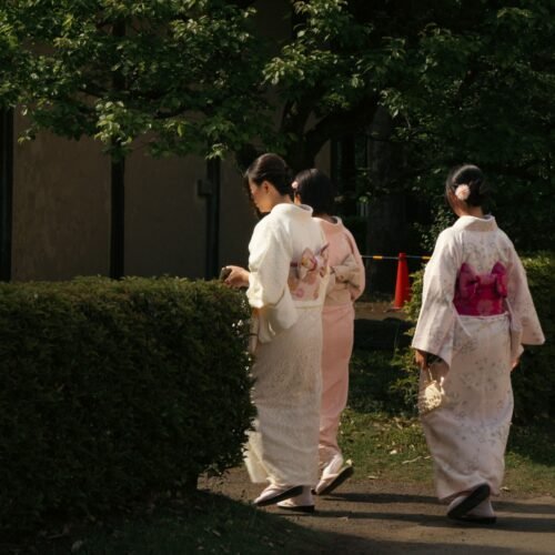 Three women in traditional kimonos strolling in a serene Tokyo garden, capturing cultural elegance.