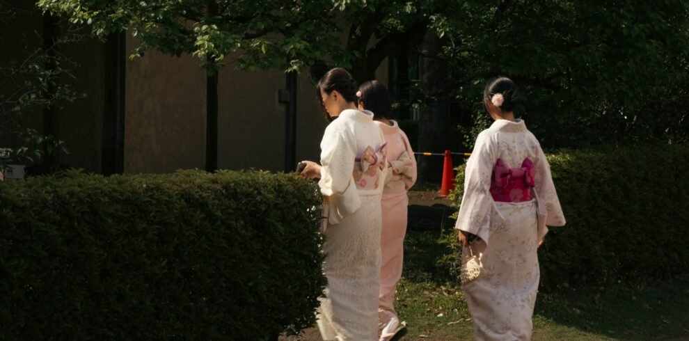 Three women in traditional kimonos strolling in a serene Tokyo garden, capturing cultural elegance.
