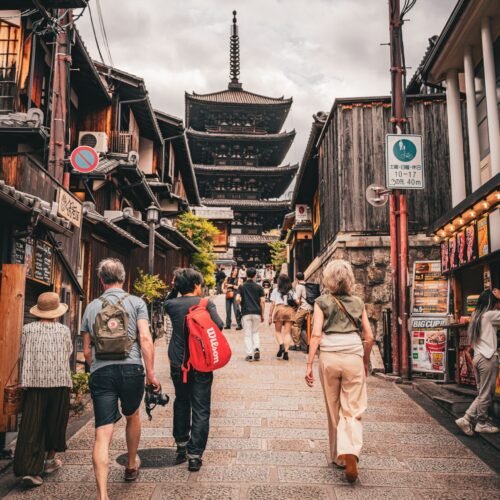 Tourists stroll down a historic street towards the iconic Yasaka Pagoda in Kyoto, Japan, showcasing traditional architecture.