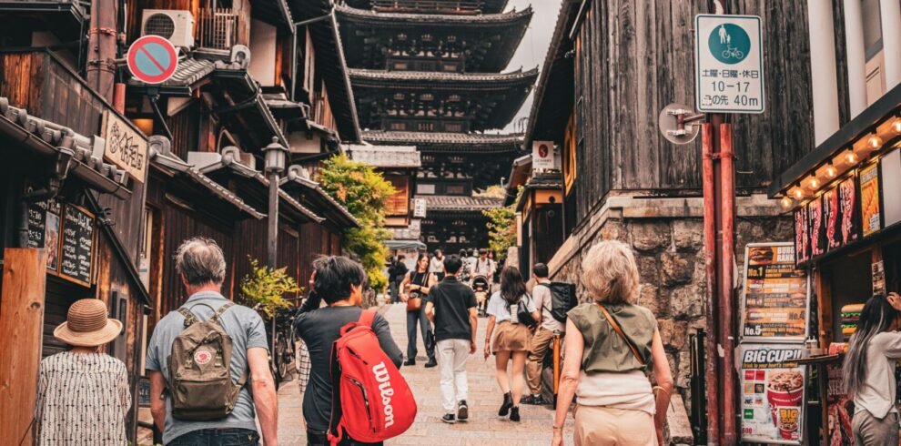 Tourists stroll down a historic street towards the iconic Yasaka Pagoda in Kyoto, Japan, showcasing traditional architecture.