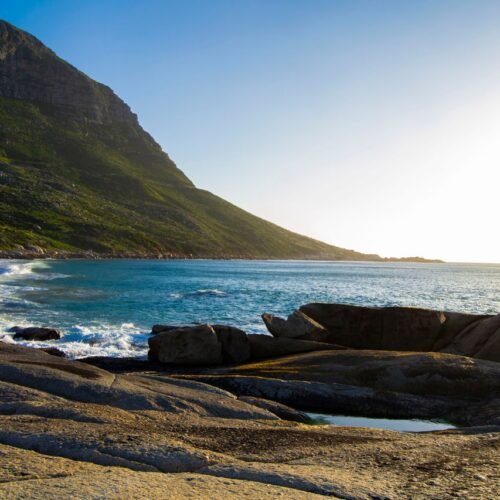 Tranquil coastal landscape of a rocky shore with mountains in South Africa.