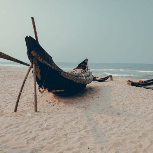 Traditional fishing boats on a sandy beach in Hue, Vietnam, with a serene ocean backdrop.