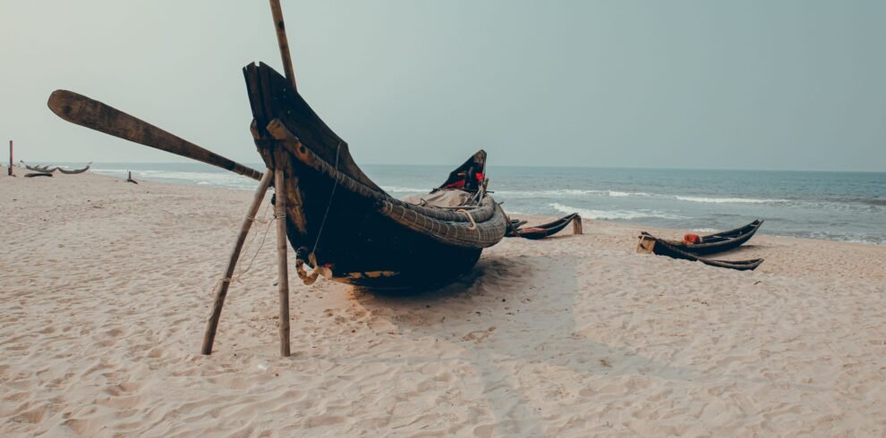 Traditional fishing boats on a sandy beach in Hue, Vietnam, with a serene ocean backdrop.