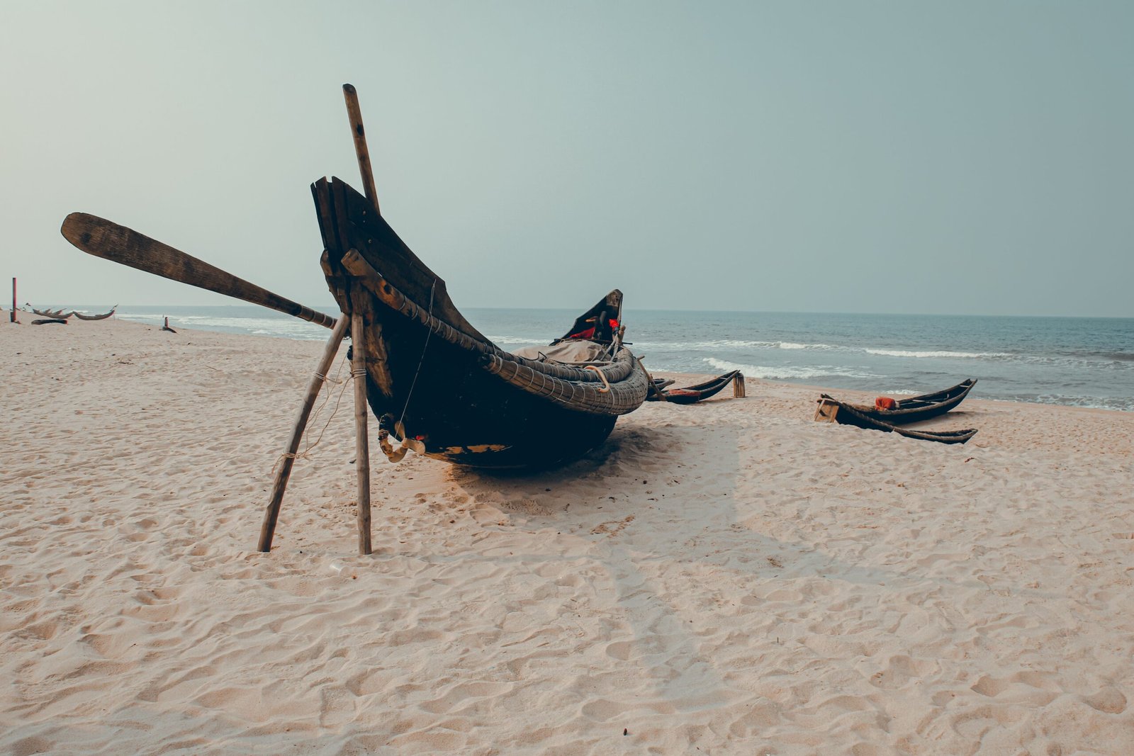 Traditional fishing boats on a sandy beach in Hue, Vietnam, with a serene ocean backdrop.