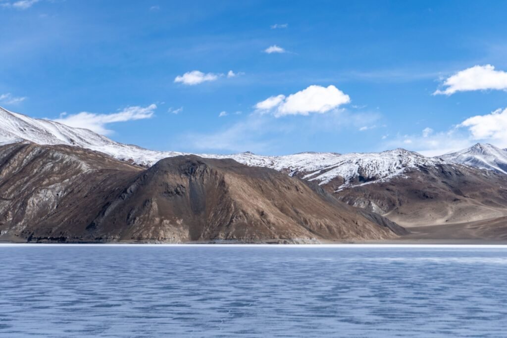 Beautiful snow-capped mountains with a frozen lake under a clear blue sky.