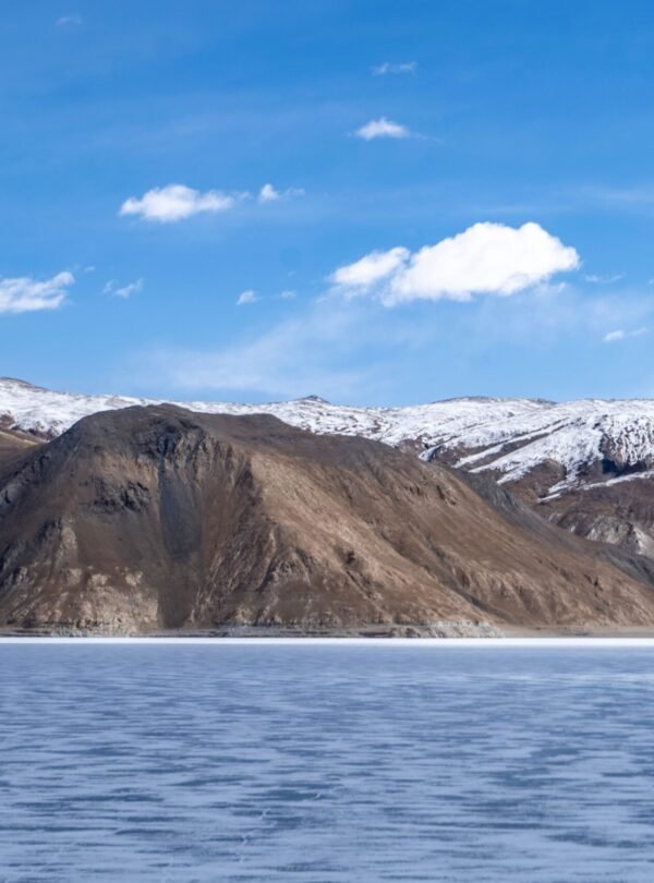 Beautiful snow-capped mountains with a frozen lake under a clear blue sky.